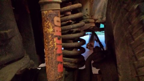 1978 Ford Bronco - Close-up view of a vehicle's suspension system, showing a rusty shock and coil spring.