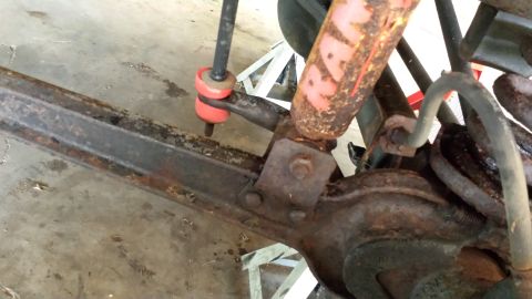 1978 Ford Bronco - Close-up view of heavily rusted vehicle suspension parts, including a shock absorber and bushings.