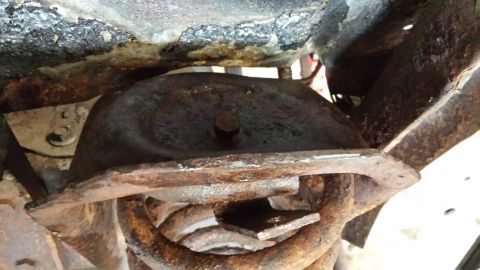 1978 Ford Bronco - Close-up view of heavily rusted vehicle suspension parts, including a coil spring.