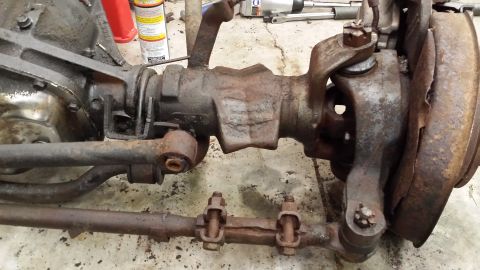 1978 Ford Bronco - Close-up view of a rusty front axle assembly and steering components.