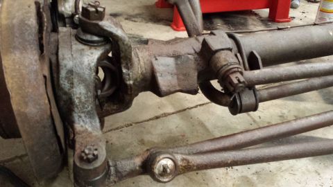 1978 Ford Bronco - Close-up view of a rusty front axle and steering linkage, likely from an older vehicle.