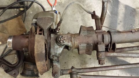 1978 Ford Bronco - Rusty front axle assembly with brake caliper and brake lines, likely from an older vehicle.