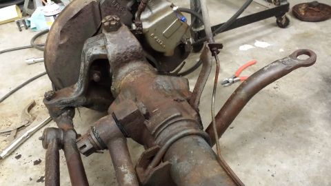 1978 Ford Bronco - Close-up view of a heavily rusted front axle assembly, including a brake caliper and associated lines, likely undergoing restoration or rep…