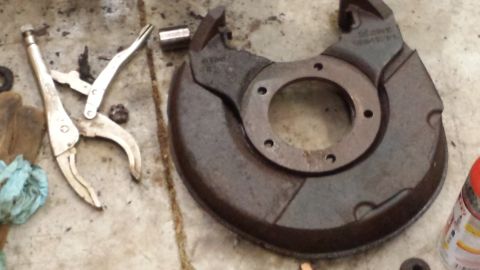 1978 Ford Bronco - A brake dust shield lies on a concrete floor next to tools.