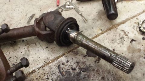 1978 Ford Bronco - Close-up of a driveshaft U-joint and axle shaft assembly on a workshop floor.