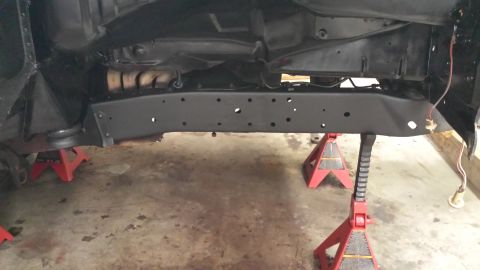 1978 Ford Bronco - The undercarriage of a 1978 Ford Bronco is visible, supported by red jack stands, revealing the frame and exhaust system.