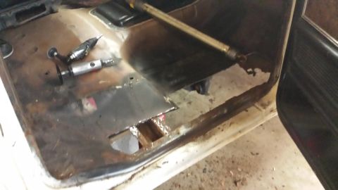 1978 Ford Bronco - Repairing rusted floor pan with tools and metal patch in vehicle interior.