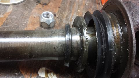 1978 Ford Bronco - Close-up of a greasy axle shaft with seals and a lug nut, likely from a vehicle repair.