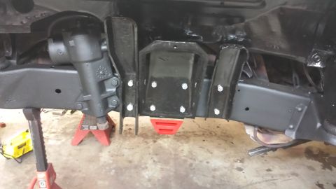 1978 Ford Bronco - Undercarriage view of a vehicle's frame, steering box, and suspension parts, supported by jack stands.