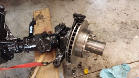 1978 Ford Bronco - Front axle assembly with disc brake rotor and hub, painted black, resting on wooden blocks.