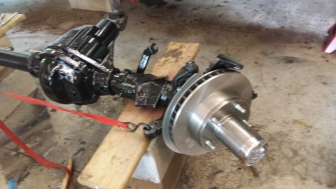 1978 Ford Bronco - A black front axle assembly with a new disc brake rotor is shown, resting on wooden supports.