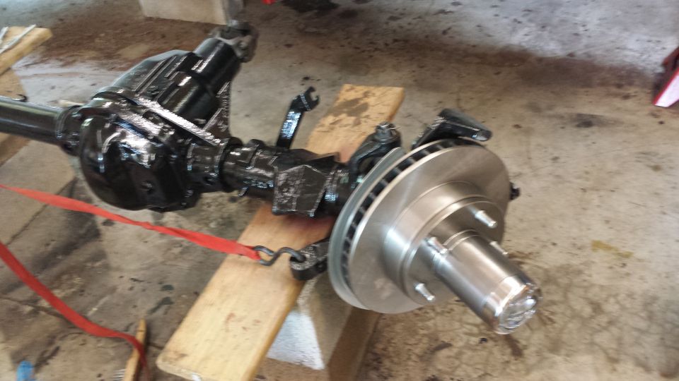 Front axle assembly with disc brake rotor and caliper bracket, supported by wooden blocks