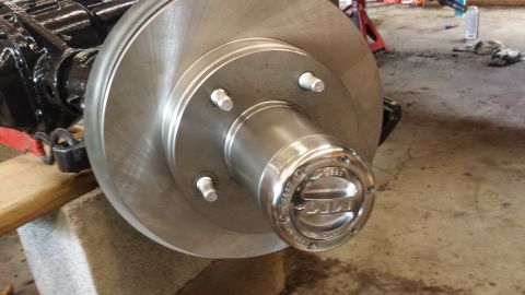 1978 Ford Bronco - Close-up of a shiny Ford Bronco hubcap on a brake rotor assembly, likely for a 1978 model.