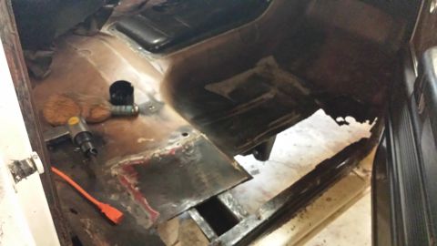 1978 Ford Bronco - Interior floor pan showing rust and repair work, with tools present.