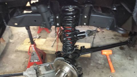1978 Ford Bronco - Close-up view of vehicle suspension parts being worked on, with tools and jack stands present.