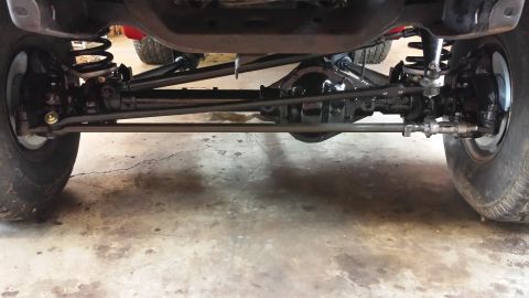 1978 Ford Bronco - The photo shows the front axle, steering linkage, and suspension of a vehicle, with another vehicle partially visible behind it.