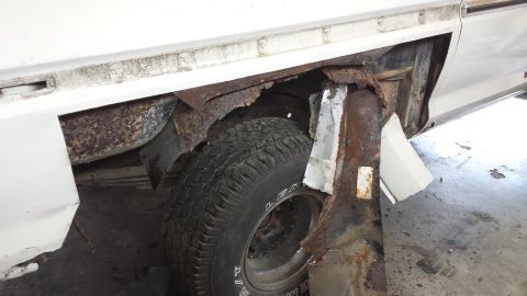 1978 Ford Bronco - The rear wheel well of a vehicle is heavily corroded, with visible rust and missing body panels.
