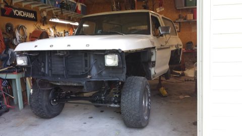 1978 Ford Bronco - This 1978 Ford Bronco is undergoing repairs in a garage, with its front end disassembled and the vehicle elevated.