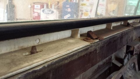 1978 Ford Bronco - Close-up of a window channel with visible rust and fasteners, likely from a vehicle.