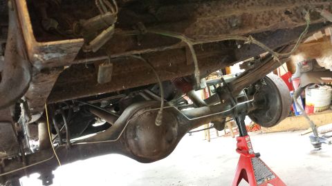 1978 Ford Bronco - Underside view of a 1978 Ford Bronco's rear axle and suspension system, supported by jack stands.