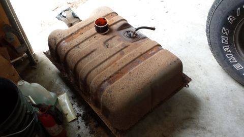 1978 Ford Bronco - A rusty fuel tank sits on a surface, with a tire visible to the right.
