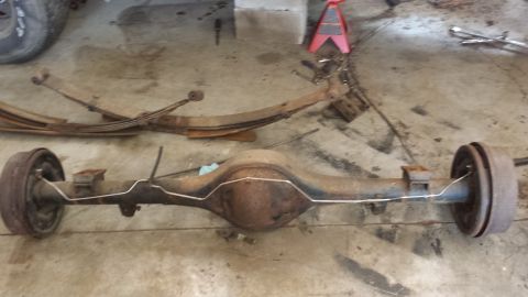 1978 Ford Bronco - A disassembled rear axle assembly and leaf springs are shown on a garage floor.