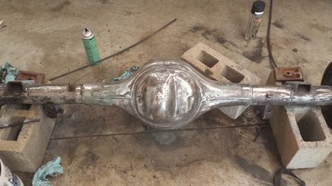 1978 Ford Bronco - A rear axle assembly rests on cinder blocks, with spray cans and rags nearby.