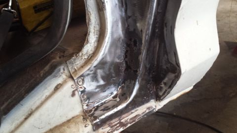 1978 Ford Bronco - Close-up of a vehicle's body panel undergoing repair with visible welding marks and primer.