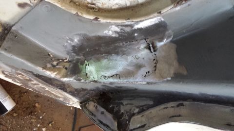1978 Ford Bronco - This image shows a close-up view of rusted metal that has undergone welding repairs, indicating restoration work on a vehicle component.