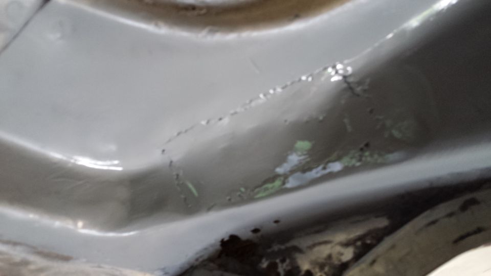 Close-up of vehicle underbody showing metal and some paint damage