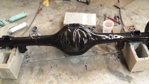 1978 Ford Bronco - Rear axle assembly painted black and drying on cinder blocks in a workshop.