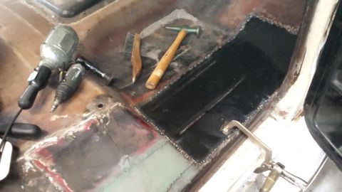 1978 Ford Bronco - Floor pan repair in progress with welding and grinding tools nearby.