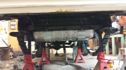 1978 Ford Bronco - The undercarriage of a 1978 Ford Bronco is shown, supported by jack stands, with the fuel tank and leaf springs clearly visible.
