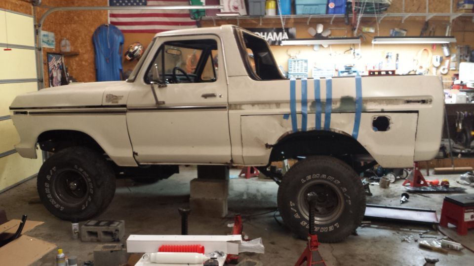 White 1978 Ford Bronco side view, raised on blocks in garage
