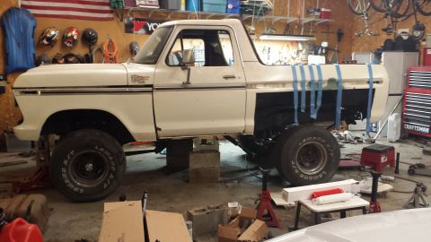 1978 Ford Bronco - A white 1978 Ford Bronco is undergoing repairs in a workshop, elevated on blocks and jack stands.