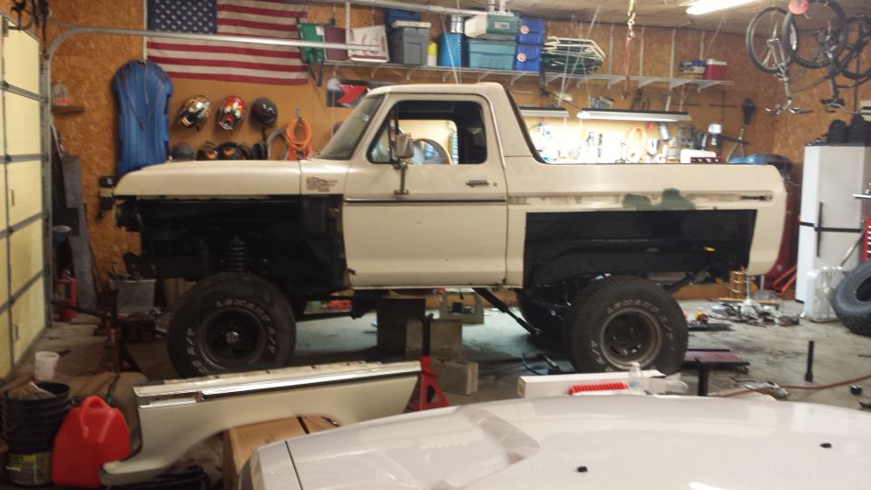 White 1978 Ford Bronco lifted in a garage with front end removed