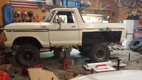 1978 Ford Bronco - A white 1978 Ford Bronco is undergoing repairs in a cluttered garage, with its rear body panels missing.