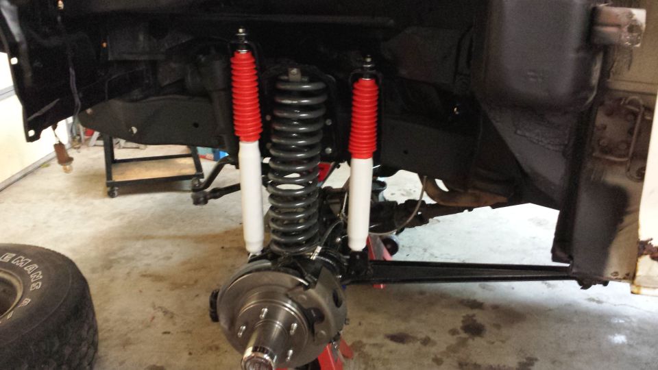 Front suspension assembly with new red and white shock absorbers and coil springs. Disc brake rotor visible