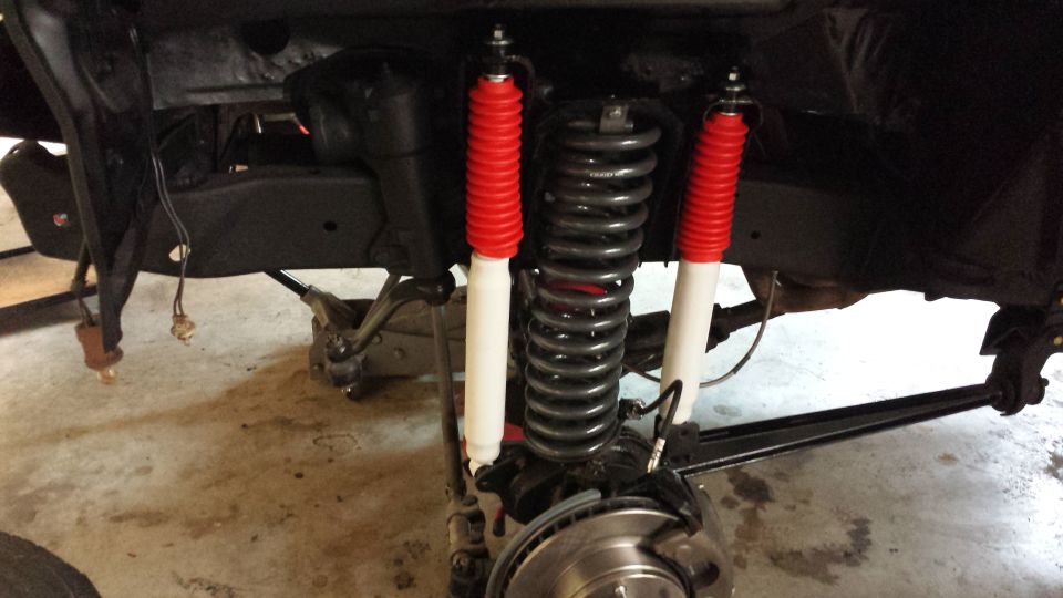 Close-up of front suspension with red-cased shocks and coil springs