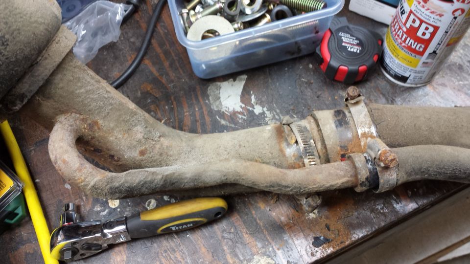 Exhaust pipe section with hose clamps and a ratchet tool on a workbench