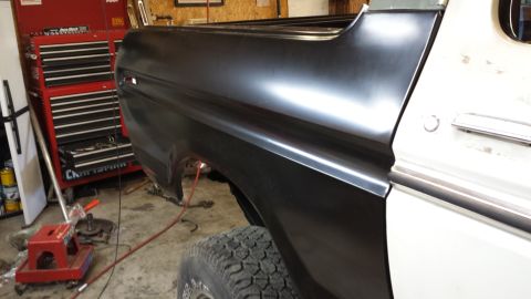 1978 Ford Bronco - The rear quarter panel of a 1978 Ford Bronco is shown unpainted next to a white door.