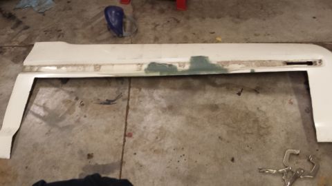 1978 Ford Bronco - A white car fender, showing signs of repair with body filler, rests on a garage floor.