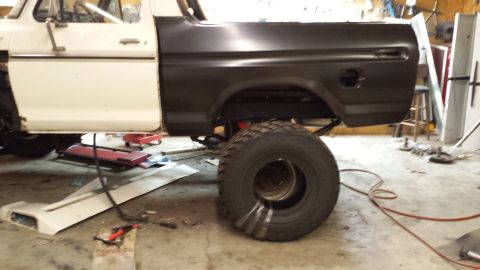 1978 Ford Bronco - This Ford Bronco is in a garage, possibly being repaired or modified, with a large tire visible.