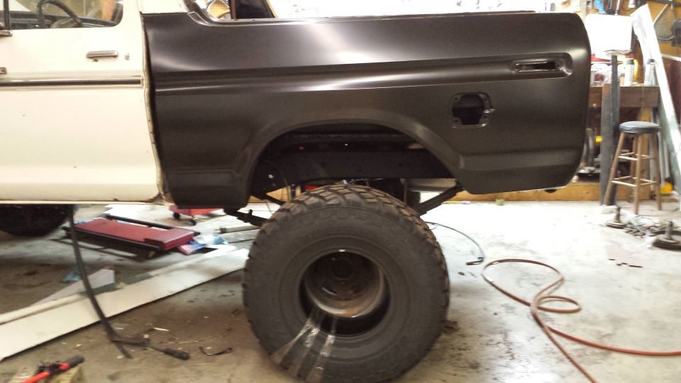 White and black 1978 Ford Bronco rear quarter panel, lifted, with large tire