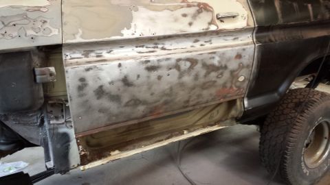 1978 Ford Bronco - The side of a 1978 Ford Bronco shows significant rust and primer during bodywork.