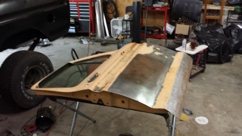 1978 Ford Bronco - A car door is being worked on in a cluttered garage setting.