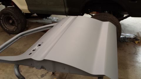 1978 Ford Bronco - A car door is prepared for painting, with parts of a vehicle visible behind it.