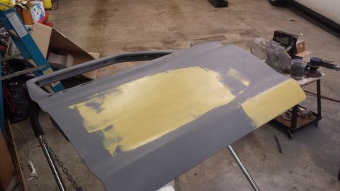 1978 Ford Bronco - A car door is being prepped for paint with body filler on its surface.