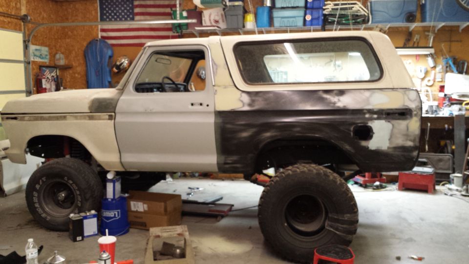 1978 Ford Bronco in primer, side view, undergoing repairs