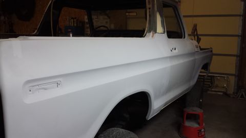 1978 Ford Bronco - The body of a 1978 Ford Bronco is shown in primer, ready for paintwork in a garage setting.